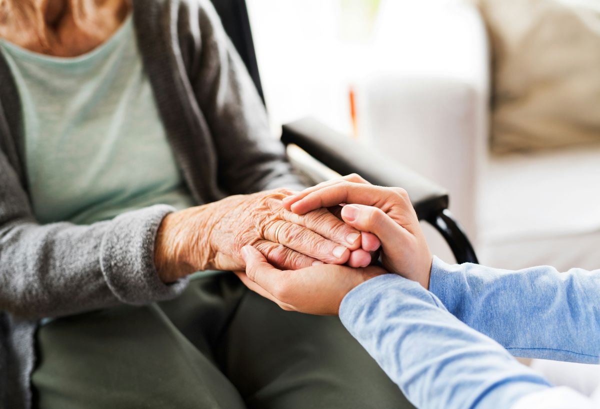 Elderly women holding hands with a person