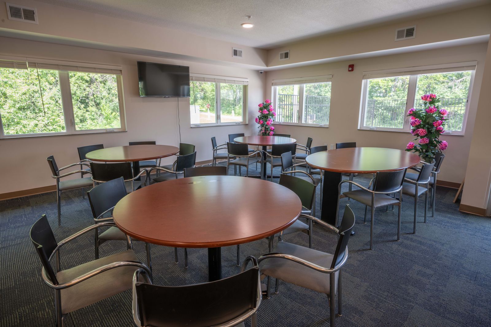 Sunny dining room with round tables and windows on three sides
